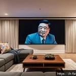 가족과 함께하는 해외 영화 감상 - A cozy modern home theater setup in a spacious living room with a large wall-mounted projector scree...